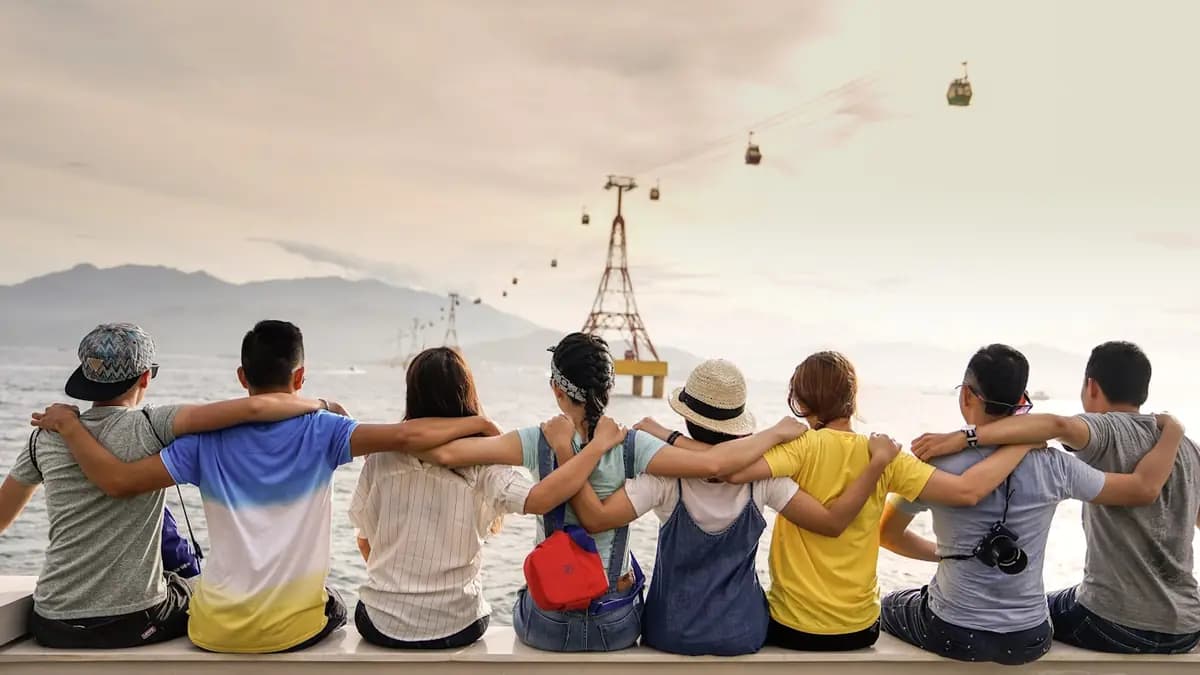 Nhóm bạn du lịch ngồi ngắm biển và cáp treo từ trên tường đá